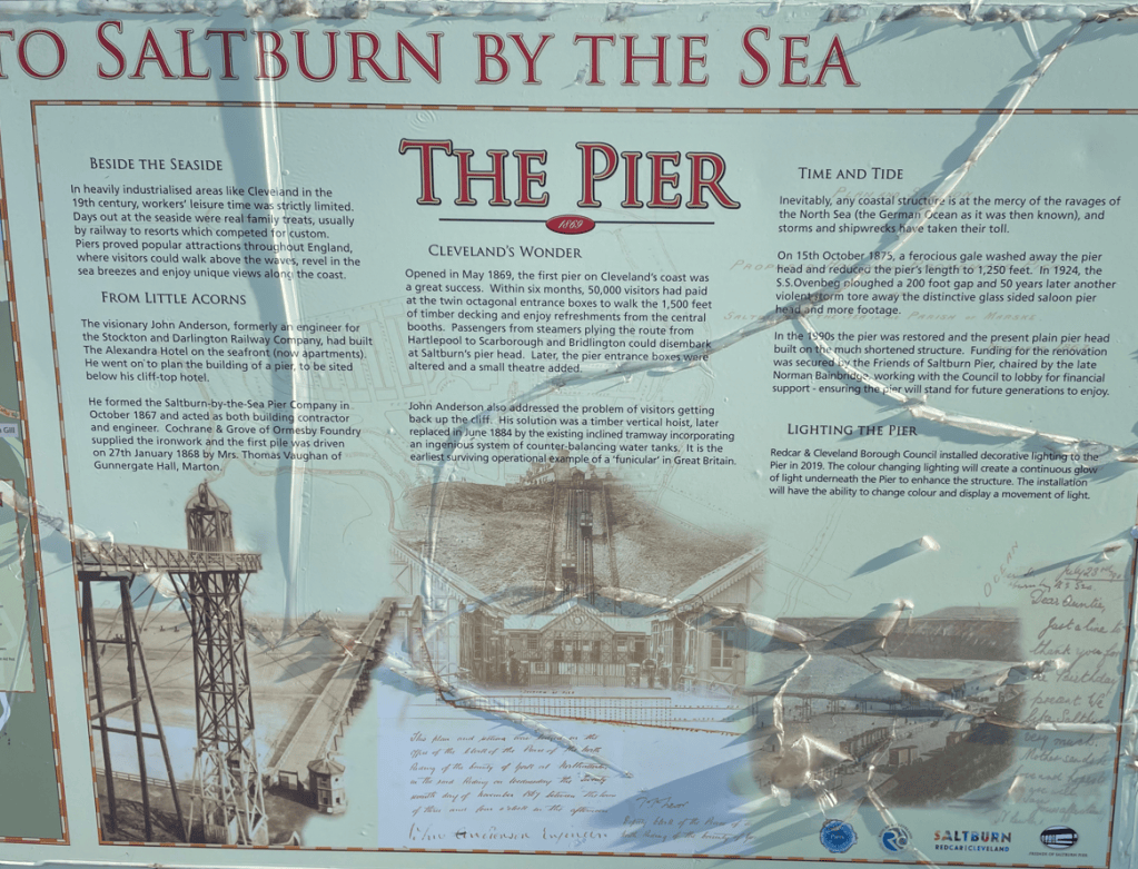 Information plaque about Saltburn Pier, detailing its history, construction, and renovations, featuring text and images related to the pier's significance and features.