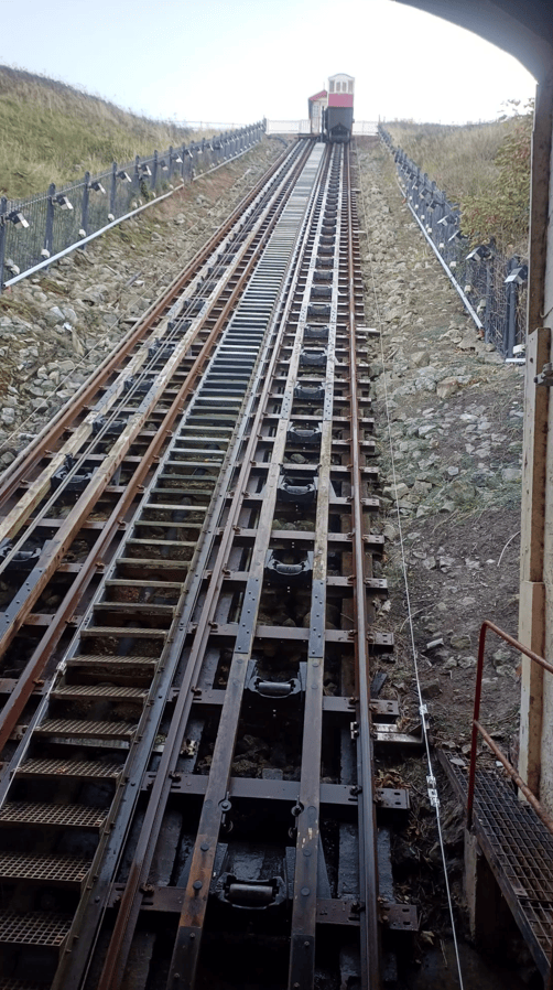 View of a steep hillside railway track leading upwards with a cabin at the top.