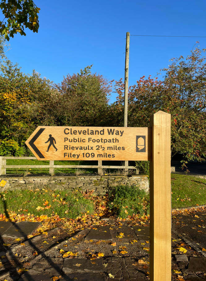 Wooden signpost for Cleveland Way footpath indicating distances to Rievaulx (21.5 miles) and Filey (109 miles), with pedestrian symbol.